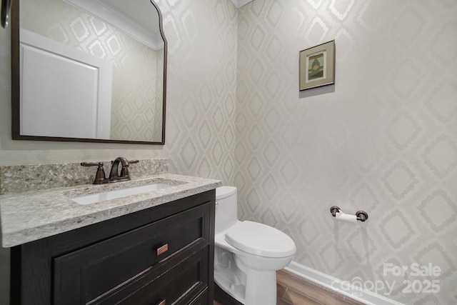 bathroom featuring toilet, ornamental molding, wood-type flooring, and vanity