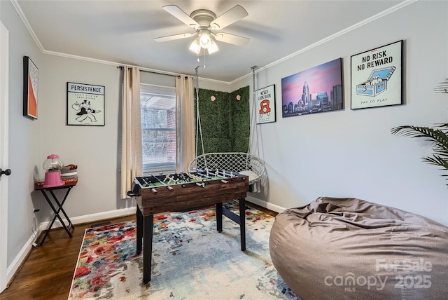 game room with crown molding, dark wood-type flooring, and ceiling fan