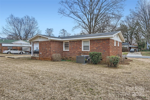 view of side of home with a carport, central AC, and a lawn