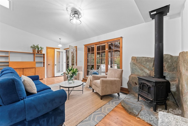 living room featuring lofted ceiling, hardwood / wood-style floors, and a wood stove