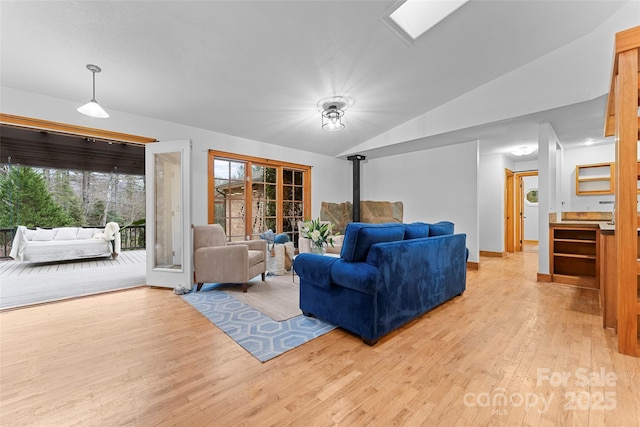 living room with lofted ceiling, light hardwood / wood-style floors, and a wood stove