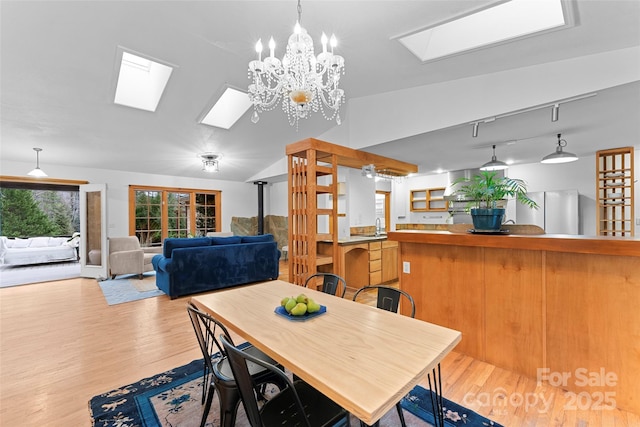 dining space featuring lofted ceiling with skylight and light wood-type flooring