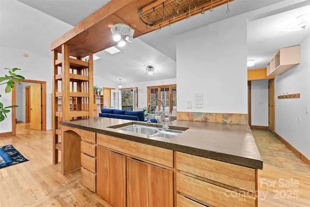 kitchen featuring lofted ceiling, light brown cabinetry, sink, kitchen peninsula, and light hardwood / wood-style floors