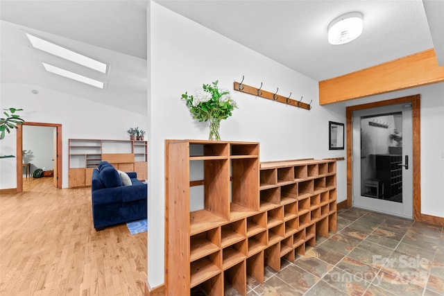 interior space with lofted ceiling with skylight and hardwood / wood-style floors