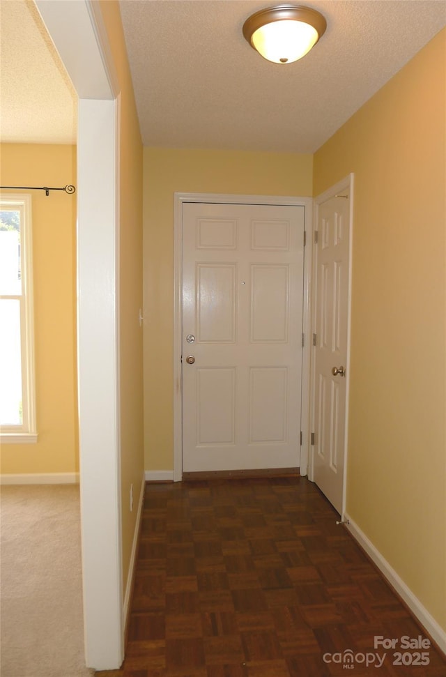 corridor with dark parquet flooring and a textured ceiling