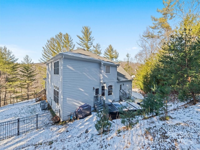 snow covered house featuring cooling unit