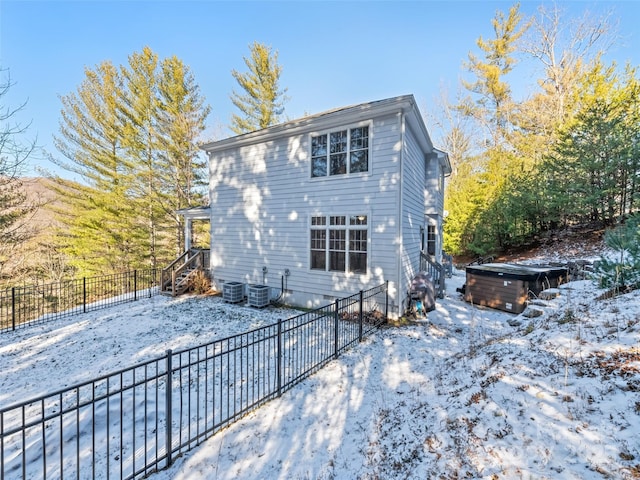 snow covered property featuring cooling unit and a hot tub