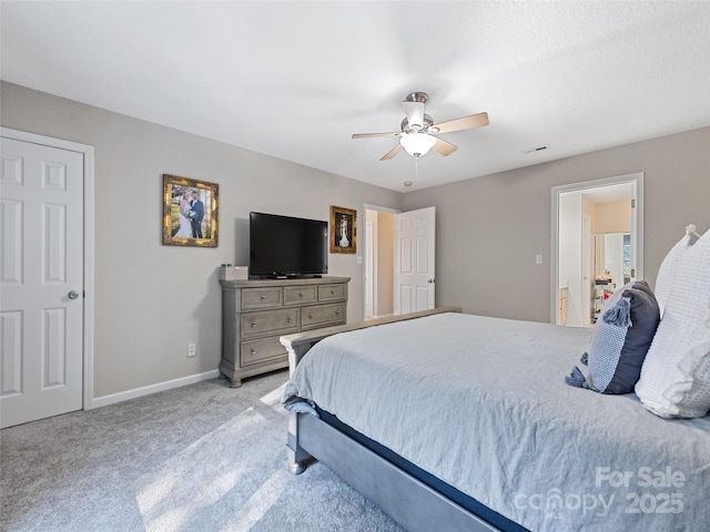 bedroom with ceiling fan, ensuite bath, and light carpet