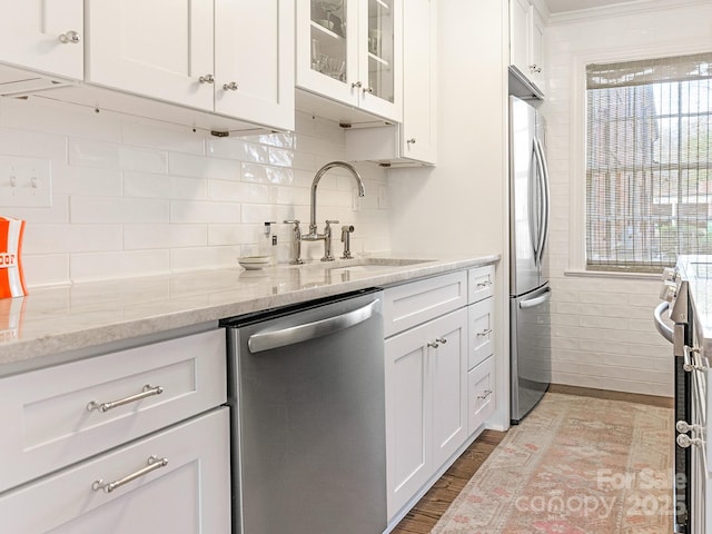 kitchen with white cabinetry, sink, light stone counters, light hardwood / wood-style floors, and stainless steel appliances