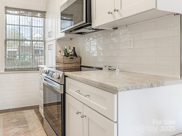 kitchen featuring white cabinetry, decorative backsplash, stainless steel appliances, and light stone counters