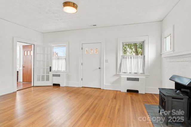 living room featuring radiator, hardwood / wood-style flooring, a textured ceiling, and a wood stove