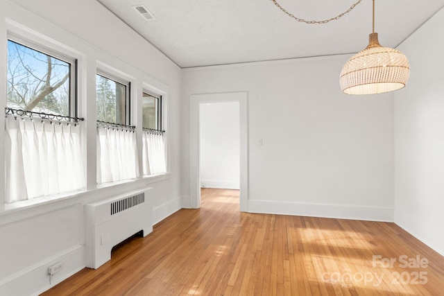 empty room featuring hardwood / wood-style flooring and radiator heating unit