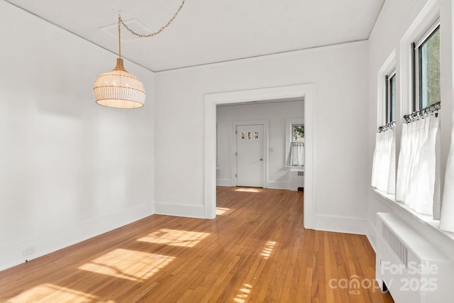 unfurnished dining area with hardwood / wood-style flooring and radiator