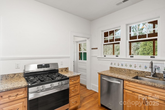 kitchen featuring stainless steel appliances, light stone countertops, sink, and light hardwood / wood-style floors