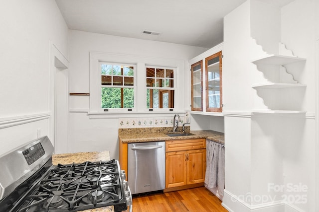 kitchen featuring stone countertops, sink, light hardwood / wood-style floors, and appliances with stainless steel finishes