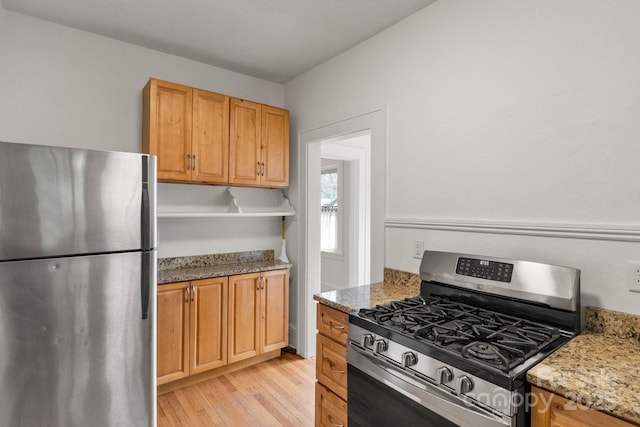 kitchen featuring appliances with stainless steel finishes, light wood-type flooring, and light stone counters