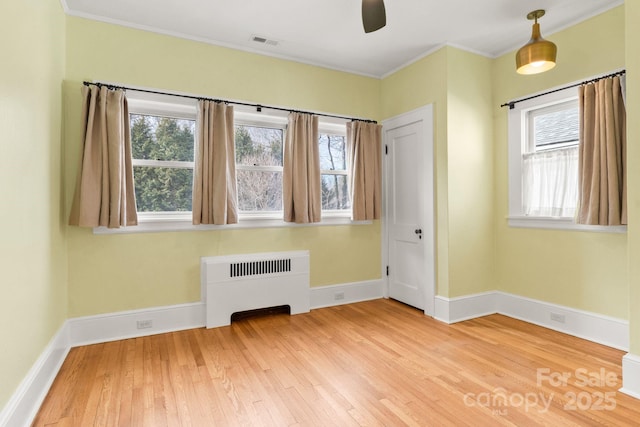 interior space with hardwood / wood-style flooring, ceiling fan, radiator heating unit, and ornamental molding