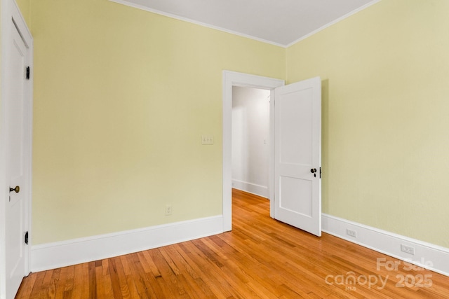 empty room with ornamental molding and light wood-type flooring