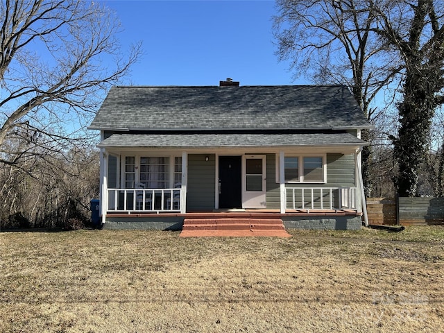 bungalow-style home featuring covered porch and a front lawn