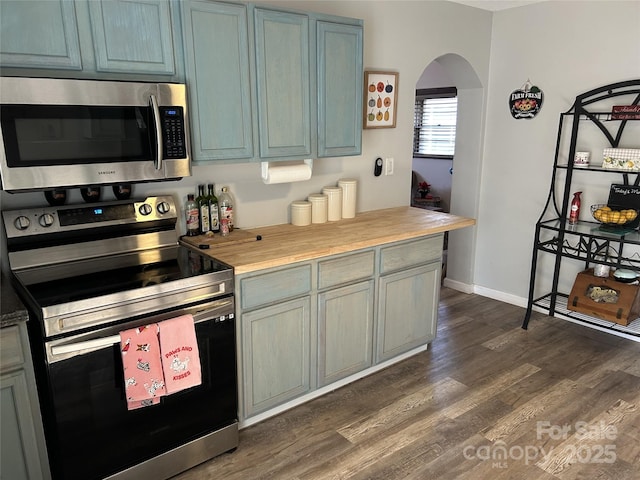 kitchen featuring dark wood-type flooring, appliances with stainless steel finishes, and wooden counters