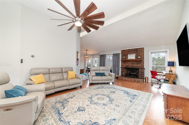 living room with a brick fireplace, vaulted ceiling with beams, and light wood-type flooring