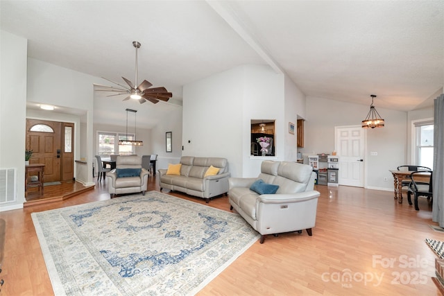 living room with an inviting chandelier, lofted ceiling, and light hardwood / wood-style flooring