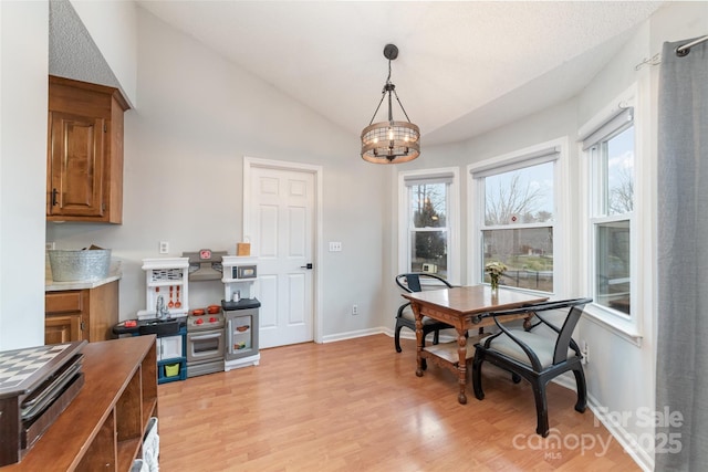 dining area with lofted ceiling, a wealth of natural light, light hardwood / wood-style flooring, and a notable chandelier