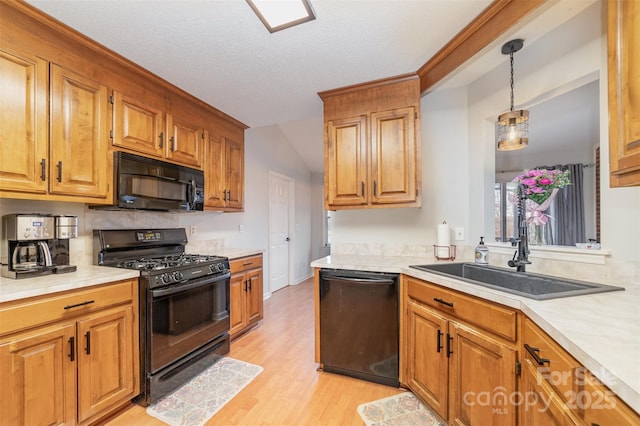 kitchen with pendant lighting, sink, light hardwood / wood-style floors, black appliances, and a textured ceiling