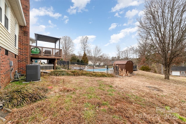 view of yard with cooling unit, a pool side deck, and a shed