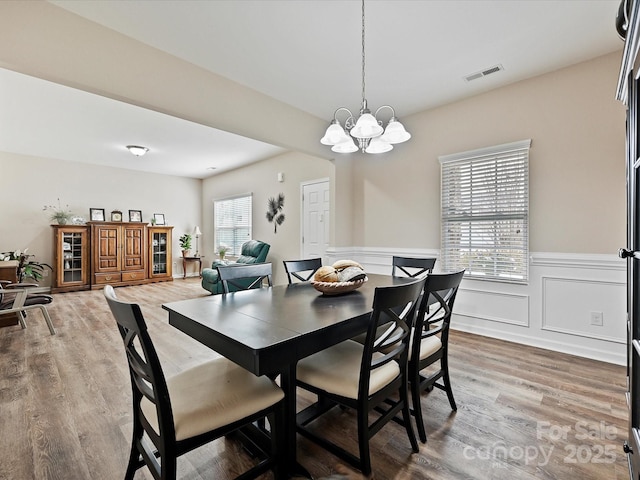 dining space with hardwood / wood-style flooring and a notable chandelier