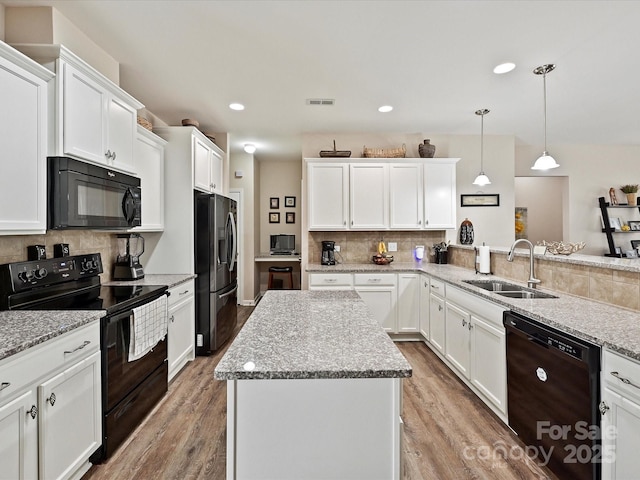 kitchen with black appliances, a kitchen island, decorative backsplash, sink, and hanging light fixtures