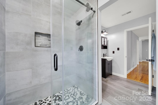 bathroom featuring wood-type flooring, walk in shower, and vanity