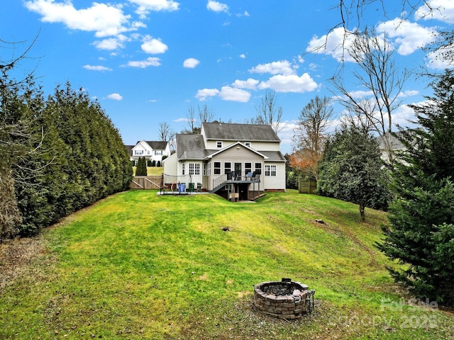 rear view of property with an outdoor fire pit, a lawn, and a deck