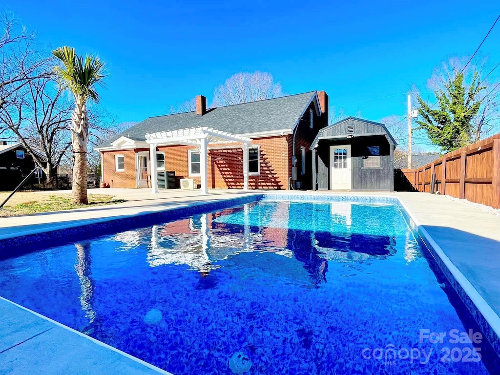 view of pool with an outbuilding and a pergola