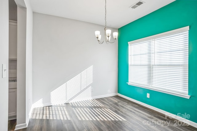 empty room with a notable chandelier and hardwood / wood-style flooring