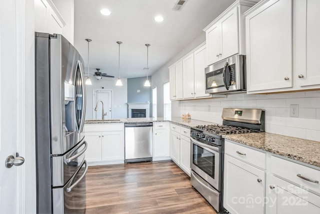 kitchen featuring decorative light fixtures, white cabinets, appliances with stainless steel finishes, and sink