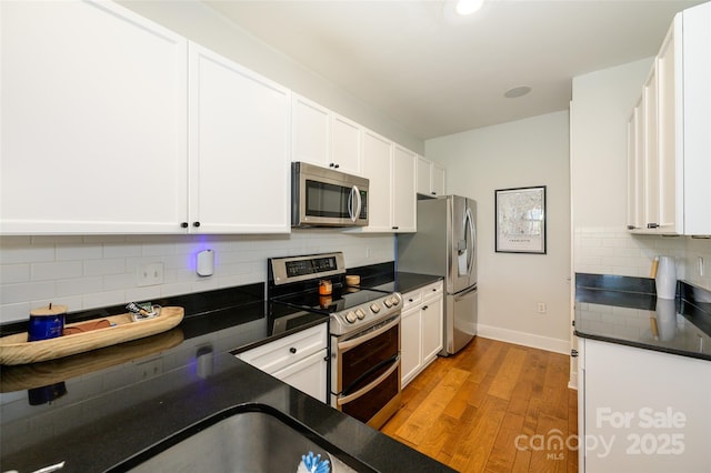 kitchen featuring light hardwood / wood-style floors, white cabinetry, appliances with stainless steel finishes, and tasteful backsplash