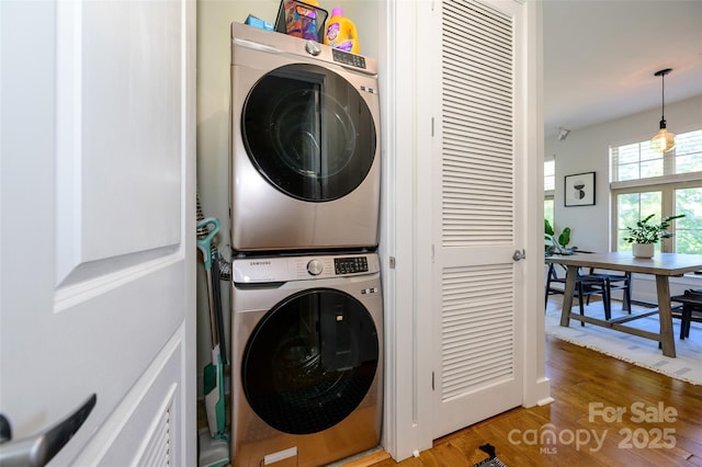 clothes washing area with hardwood / wood-style floors and stacked washer and clothes dryer