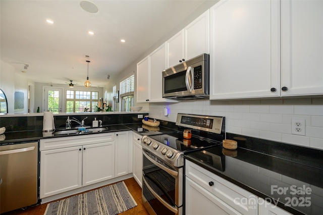 kitchen with pendant lighting, appliances with stainless steel finishes, white cabinetry, sink, and ceiling fan