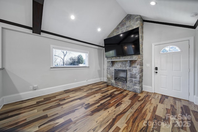 unfurnished living room featuring hardwood / wood-style flooring, vaulted ceiling, and a stone fireplace