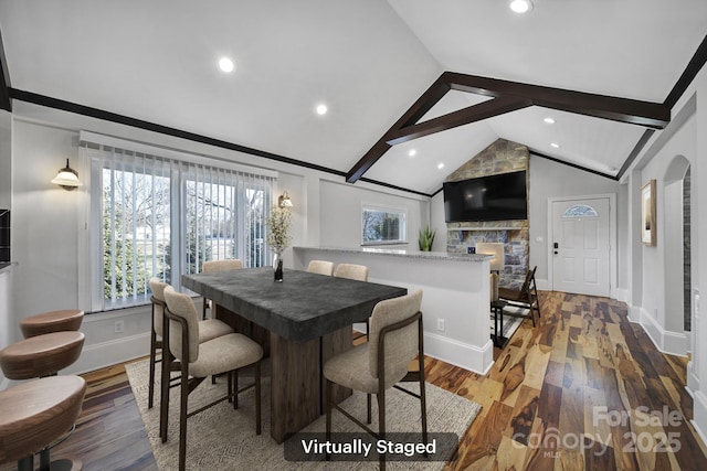 dining area featuring lofted ceiling with beams, wood-type flooring, and a fireplace