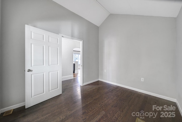 empty room with dark wood-type flooring and vaulted ceiling