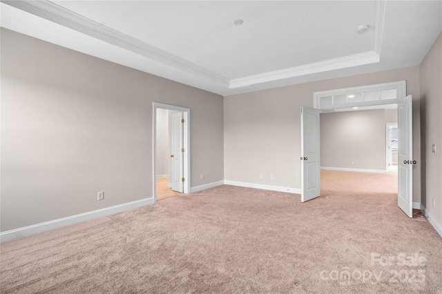 carpeted empty room featuring a raised ceiling and crown molding