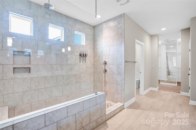 bathroom with a tile shower, wood-type flooring, and toilet