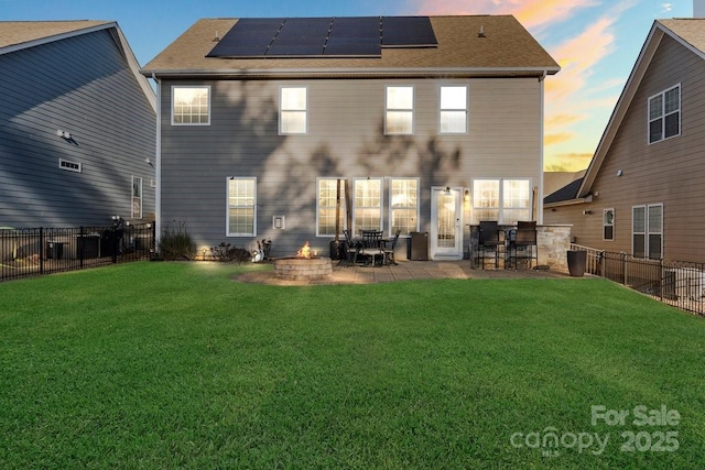 136 Margo Ln, Statesville, NC 28677 - back of house at dusk with roof mounted solar panels, an outdoor fire pit, a patio area, and a shingled roof