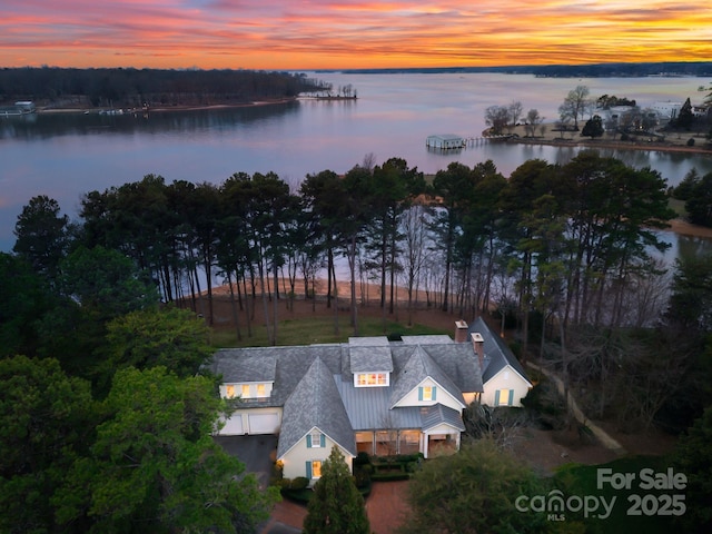 aerial view at dusk featuring a water view