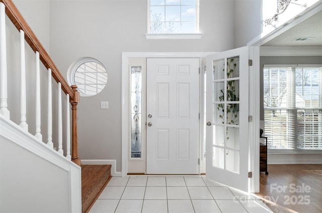 tiled entrance foyer featuring a healthy amount of sunlight and a towering ceiling