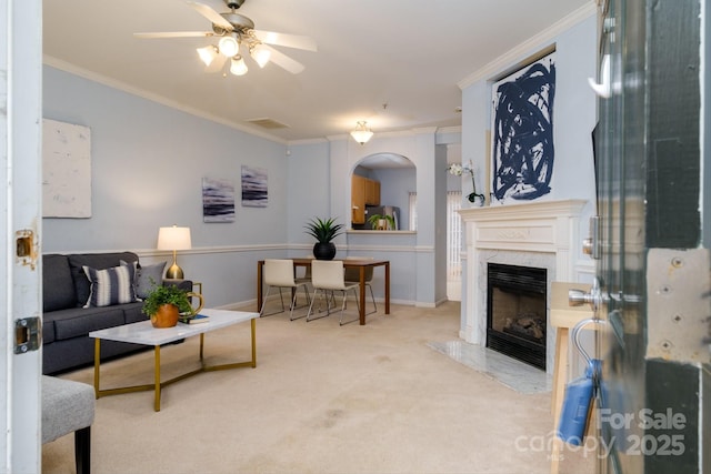 carpeted living room featuring ceiling fan, ornamental molding, and a fireplace