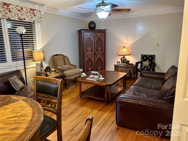 living room with wood-type flooring, ornamental molding, and ceiling fan