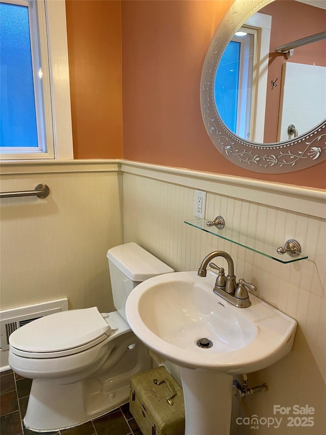 bathroom with tile patterned flooring, a baseboard heating unit, sink, and toilet